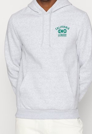 Osoba nosząca jasnoszary hoodie z kieszenią z przodu oraz zielonym nadrukiem "California League 1774 College Championship" na lewej piersi.