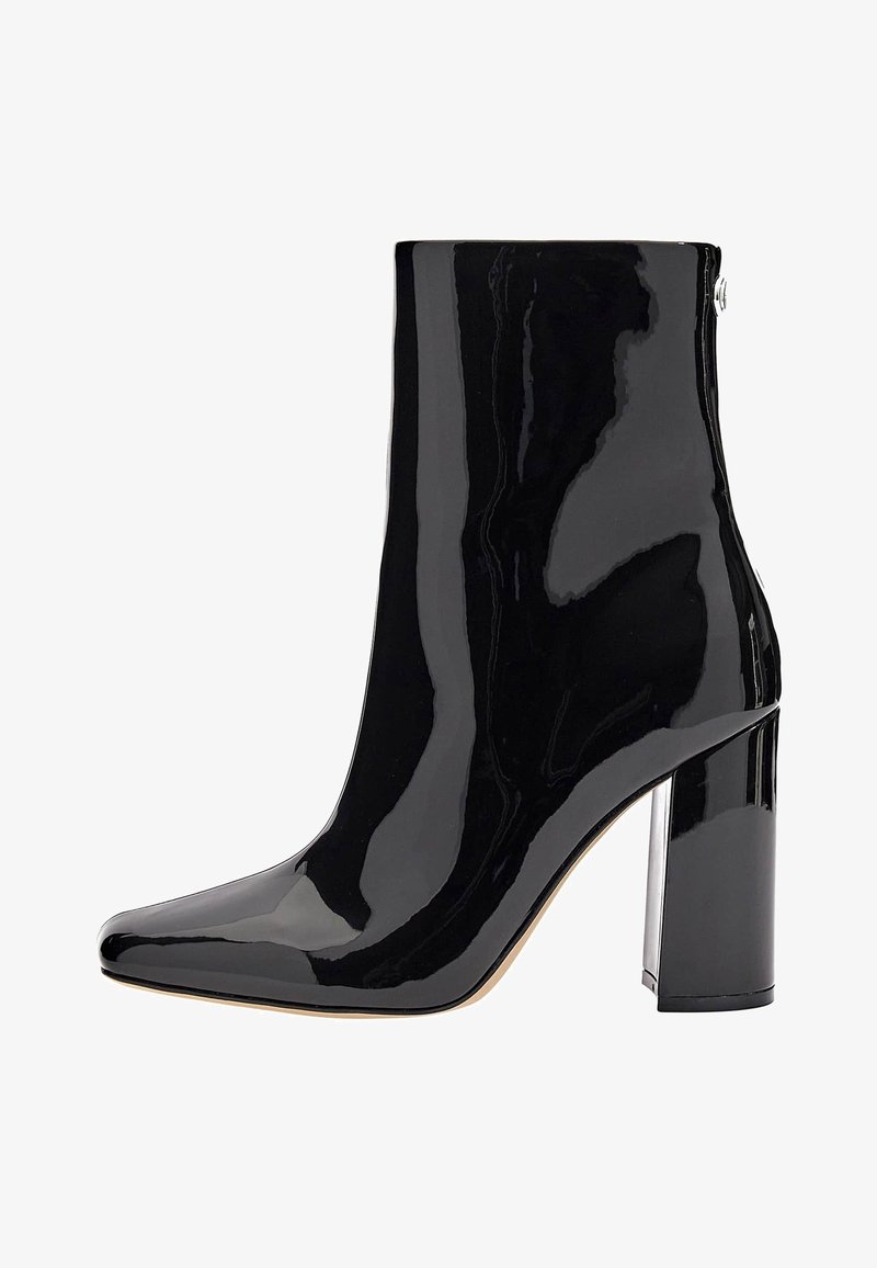 Bottine noire en cuir verni brillant avec bout pointu et talon bloc haut sur fond blanc.