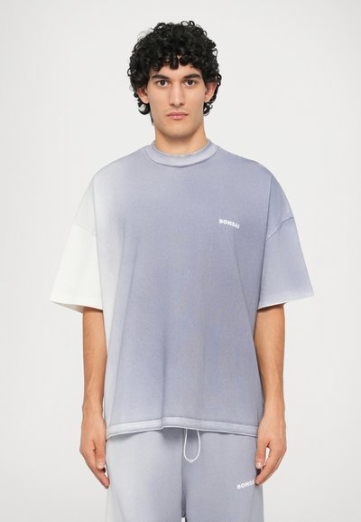 Tricou supradimensionat din bumbac în gradient albastru și alb, cu guler rotund și mâneci scurte. Detaliu cu logo pe piept.
