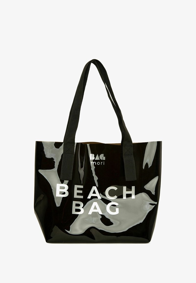 Musta kiiltävä olkalaukku, jossa on "BEACH BAG" -teksti paksuilla valkoisilla letrailla. Varustettu kestävillä mustilla kangashandleilla ja tilavalla sisäosalla.