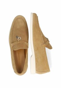 Mocassini in suede beige con punta leggermente affusolata, suola in gomma bianca, accent con hardware decorativo e dettagli di cucitura lungo i bordi.