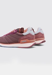 Une paire de baskets Hoff mauves et roses avec des accents blancs, des semelles texturées, et le nom de la marque sur le talon et sur le côté, inclinées pour montrer le profil extérieur.