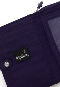 Portafoglio in tessuto viola con protezione RFID, dotato di più scomparti per carte e chiusura a scatto. Etichetta con il logo Kipling visibile. Texture liscia.