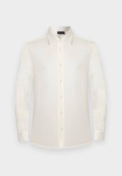 Hvit skjorte med lange ermer og knapper, med klassisk krage og liten logoemblem på venstre bryst.