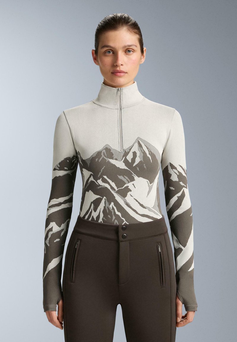 Dlhý rukáv s potlačou hôr v odtieňoch šedej a hnedej, vysoký golier a zapínanie na zips. Hladká pletená tkanina, priliehavý strih.