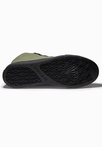Chaussure à tige en tissu vert avec semelle en caoutchouc noire. La semelle présente un motif géométrique de la bande de roulement et le nom de la marque "ombre 42" embossé sur le côté.