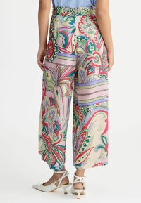 Pantalons larges et colorés avec un motif paisley dans des nuances de rose, vert et bleu, en tissu lisse et taille haute.