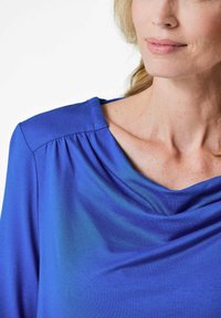 Royalblaues Stricktop mit drapierter Dekolleté, gefältelten Details an den Schultern und weicher Textur. Ideal zum Schichten oder als eigenständiges Kleidungsstück.