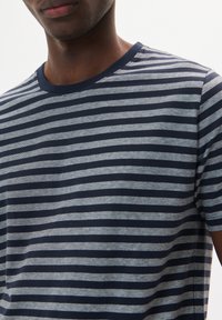 Tamsiai mėlynas ir šviesiai pilkas dryžuotas marškinėliai su apvalia iškirpte, trumpomis rankovėmis ir minkšta medvilnės tekstūra. Pasižymi laisvalaikio dizainu.