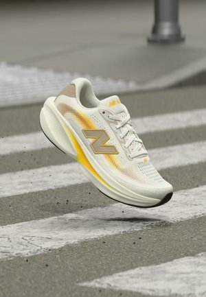 Weißer und gelber New Balance Laufschuh, der über einem Zebrastreifen mit verschwommenem Pflasterhintergrund schwebt.