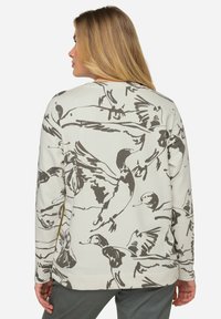Sweatshirt gris clair avec un imprimé de noir d'oiseaux. Manches longues, encolure ronde et coupe décontractée avec des détails de couture visibles.