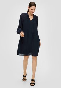 Navyblaues, plissiertes Kleid mit V-Ausschnitt, langen Ärmeln und Kordelzügen am Ausschnitt. Leichter, fließender Stoff mit einer weichen Textur.