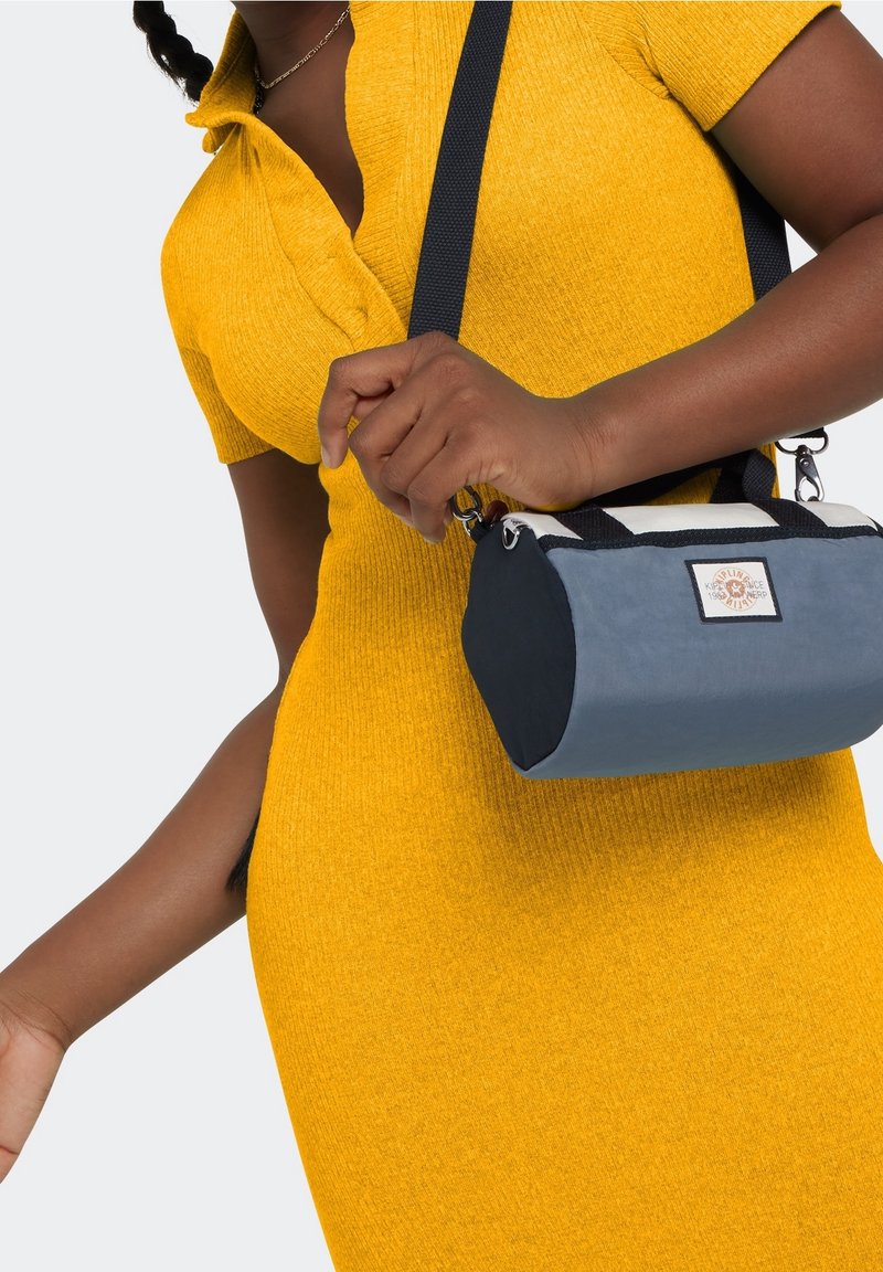 Yellow ribbed dress with a fitted design. Gray and navy compact bag with a rounded shape, black strap, and a label on the front.
