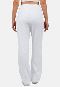 Witte, gestructureerde, loszittende broek met een elastische tailleband, vervaardigd uit een zachte, gekreukte stof en met een wide-leg ontwerp.