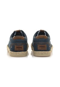 Zapatillas de lona azul con acentos de cuero marrón, suela de cuerda texturizada y un forro interior estampado. Etiqueta del logotipo visible en la parte posterior.