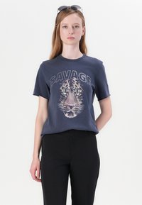 Maglietta di cotone blu navy con grafica di una leopardessa e la parola "SAVAGE" in grassetto sopra. Maniche corte, vestibilità comoda e scollo rotondo.