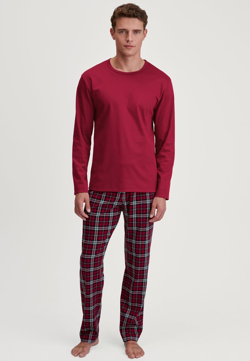 Rode langemouwtop gecombineerd met gestreepte pyjamabroek in ruitpatroon met rode, groene en blauwe lijnen. Zachte stof en een ontspannen pasvorm voor comfort.