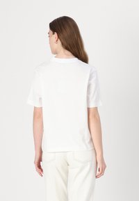 Hvid kortærmet t-shirt med rund hals, lavet af blødt stof, som har en let løs pasform. Bagansigtet viser minimale design detaljer.