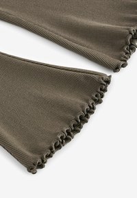 Tessuto a coste verde oliva con una superficie testurizzata e bordi arricciati. Il design presenta due strati sovrapposti con cuciture intricate.