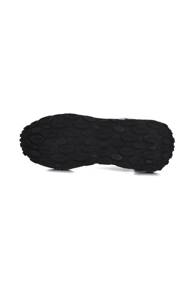 Semelle de sneaker noire présentant un motif de grip texturé avec différentes formes ovales, conçue pour la traction et le soutien.