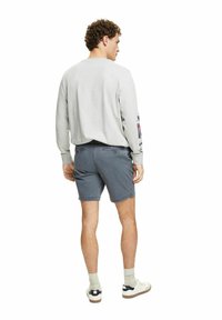 Grå langærmet skjorte med trykte detaljer, parret med navy shorts og hvide sneakers. Sættet har en afslappet pasform og klassisk design.