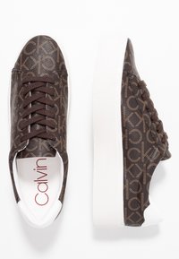 Brązowe sneakersy w wzór logo z gładkiej syntetycznej cholewki, białą gumową podeszwą i ciemnobrązowymi sznurówkami; wewnątrz posiadają branding Calvin Klein.