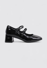 Chaussures Mary Jane en cuir verni noir avec un bout pointu, comportant deux brides décoratives avec des boutons ronds et un talon épais.
