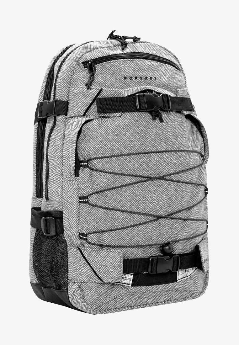Sac à dos en tissu chevron gris avec accessoires noirs, plusieurs poches zippées, des bretelles ajustables et une poche latérale en mesh pour le rangement.