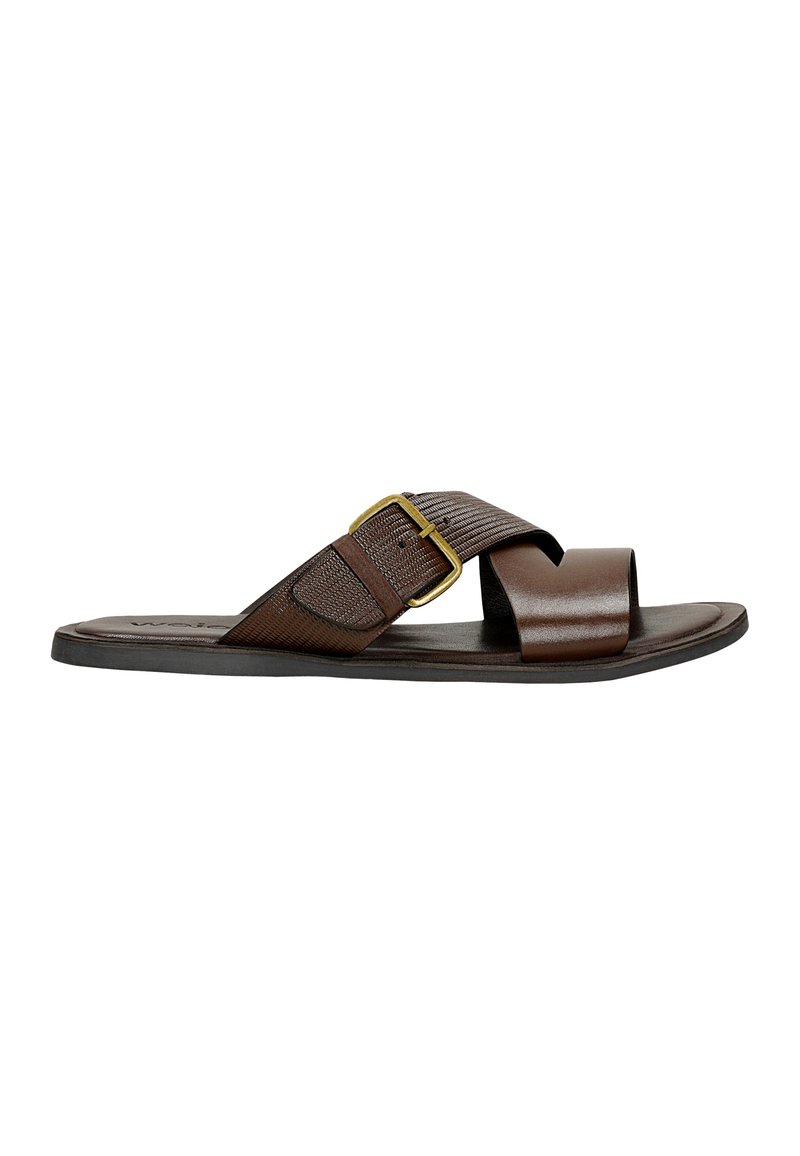 Brown leather slide sandal with a wide strap, fabric detailing, and a gold buckle accent. Flat sole with a textured footbed.