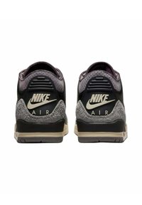 Sneaker Nike Air con tomaia nera, dettagli in suede grigio, orecchio perforato e un distintivo logo bianco sul tallone.
