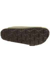 Grön platt sko med en texturerad svart gummisula, som har ett diamantrutigt mönster för bra grepp och ett mjukt ovandelsmaterial.