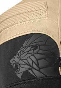 Lähedalt vaadatuna on beež kangas musta materjali peal, millel on matt ja läikiv musta värvi geomeetriline lõvi disain mustal taustal.