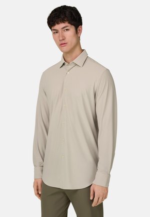 Lichtbeige overhemd met lange mouwen, knopen aan de voorkant, een zachte textuur, klassieke kraag en afgeronde zoom. Heeft gele knopen aan de voorkant.