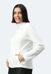 Giacca di pile bianca con colletto alto, tasche laterali e texture liscia. Presenta una chiusura con zip e maniche lunghe.