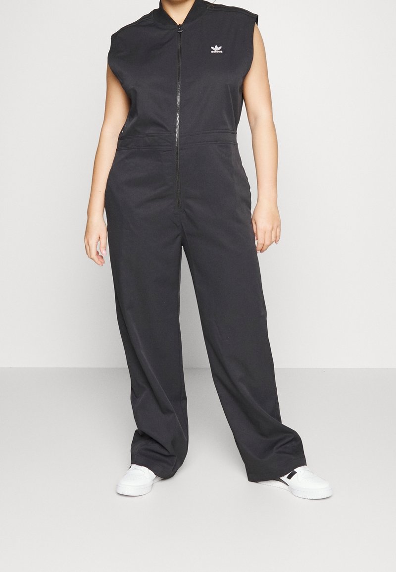 Svart ärmlös jumpsuit med dragkedja fram och elastisk midja. Har en liten logotyp på bröstet, gjord av ett mjukt tyg.