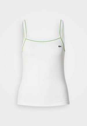 Witte mouwloze tanktop met groene piping langs de halslijn en armsgaten; heeft een klein geborduurd logo op de linkerkant van de borst.