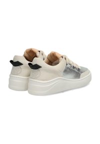 Le sneakers bianche e argentate presentano una tomaia in suede, dettagli metallici e una suola ammortizzata con un tallone sollevato e dettagli a pois.