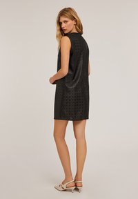Rochie neagră fără mâneci, cu un design perforat, având mici decupaje circulare. Textură fină, până la genunchi și cu o croială lejeră.