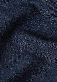 Tummansininen denim-kangas, jossa on hienovarainen rakenne, sileä kudonta ja pieni kiilto, erilaisten indigonsävyjen esittämänä.