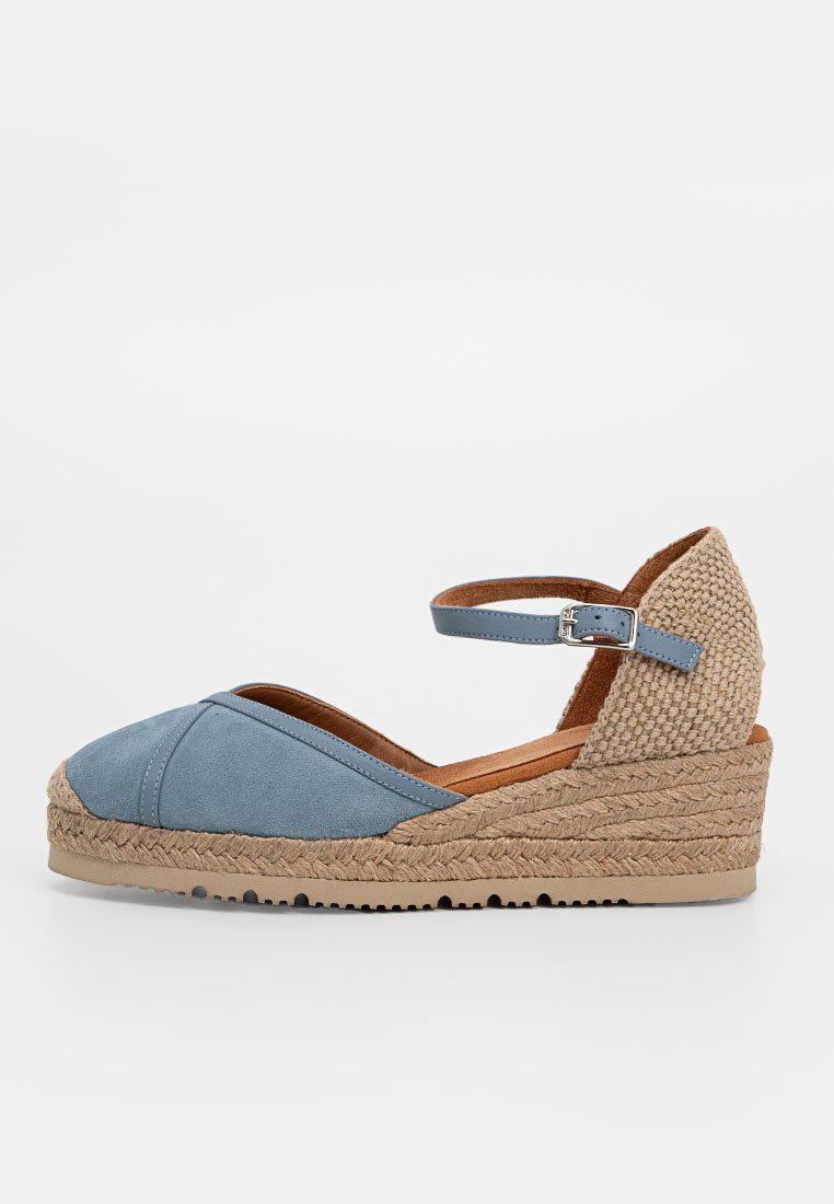 Sandaletta con tacco wedge in suede blu, con tacco in giuta intrecciata, cinturino alla caviglia e soletta marrone. Presenta una punta arrotondata e accenti naturali testurizzati.