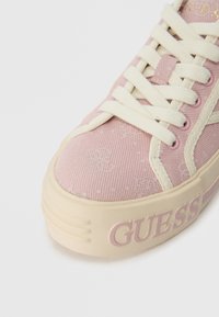 Adidași roz din pânză cu un model texturat, șireturi crem și detalii cu logo pe lateral. Au o talpă groasă bej pentru un plus de înălțime.