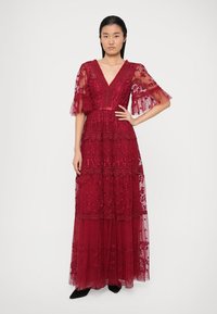 Sügavpunane maksimekko, valmistatud pitsist ja tüllist. Omab V-kaelust, lillemustreid ning kaskaadseid kihte koos läbipaistvate puhv-särgid.