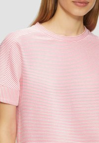 Rosa und weiße gestreifte Kurzarm-T-Shirt mit rundem Halsausschnitt und weicher Textur, der feine horizontale Linien unterschiedlicher Breite zeigt.