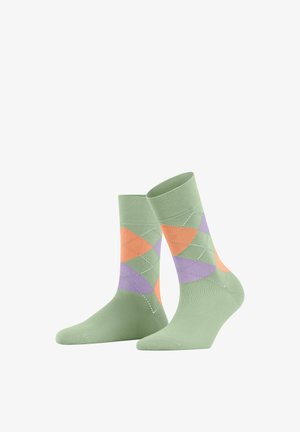 Paire de chaussettes vertes avec un motif en diamants argyle orange et violet, présentée sur un fond blanc.