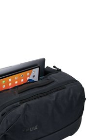 Zwarte Thule tas van een gemêleerde stof, met een rits. Een tablet is gedeeltelijk zichtbaar in de tas.