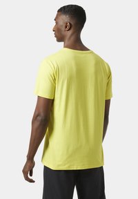 Camiseta de algodón amarilla con mangas cortas y escote redondo, con un diseño liso y un ajuste relajado, vista desde la parte de atrás.