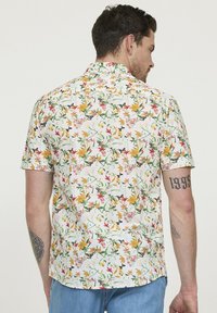 Korte mouw shirt met een witte achtergrond en een kleurrijke bloemenprint. Het materiaal is lichtgewicht, met een relaxte pasvorm en een klassieke kraag.
