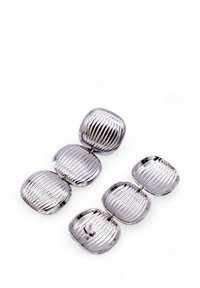 Fascette per capelli in metallo tono argento con pattern rigato, caratterizzate da una forma liscia e una finitura lucida. Disposte in una sequenza collegata.