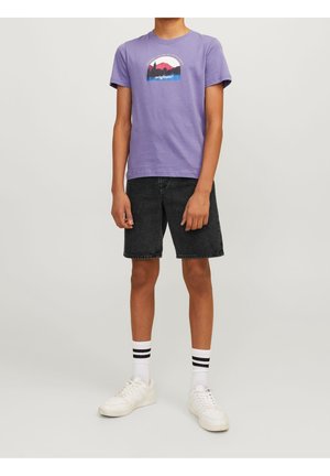 Paarse katoenen t-shirt met een grafische print van bergen en tekst. Gecombineerd met zwarte spijkershorts en witte sneakers met zwarte sokken.