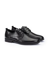 Scarpe da uomo in pelle nera con una texture liscia e perforata, dotate di lacci rotondi e una forma affusolata e elegante.